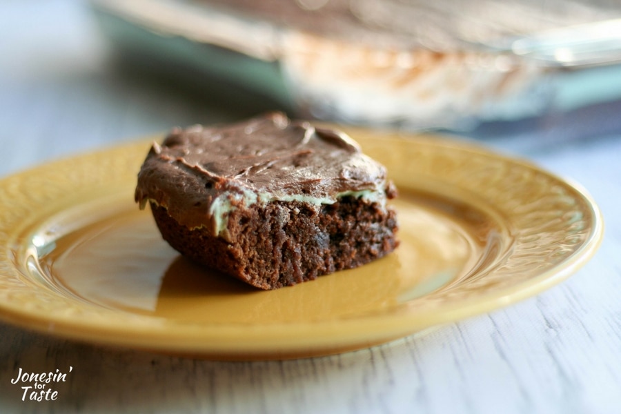 Looking at a side view of a square of mint brownie on a yellow plate