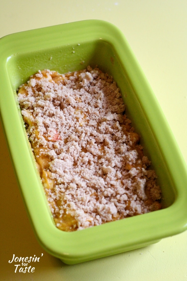 A loaf pan with bread batter sprinkled with streusel topping