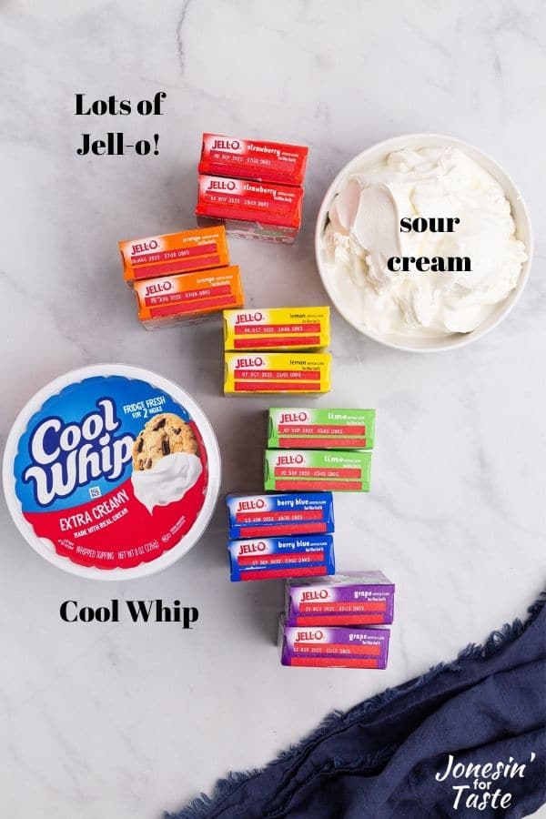 a bowl of sour cream, boxes of jello, and a tub of cool whip on a white counter