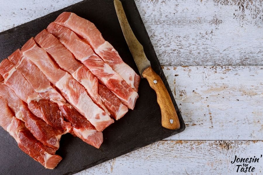 sliced pork and a knife on a black cutting board