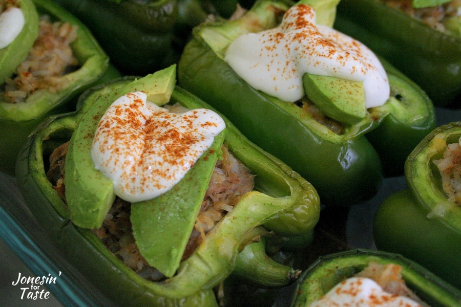 A pair of Southwest Stuffed peppers topped with avocados and lime yogurt sauce