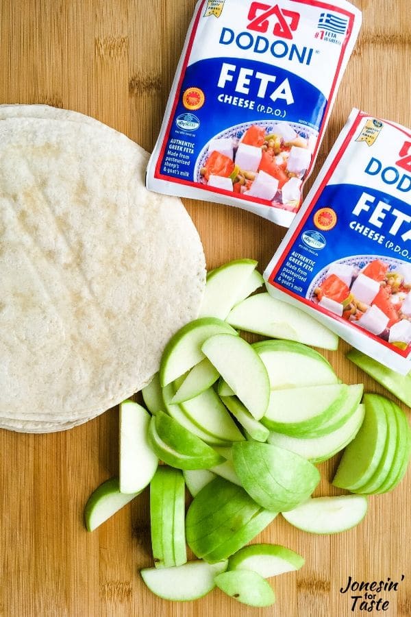 tortillas, sliced apples and feta cheese packages on a cutting board