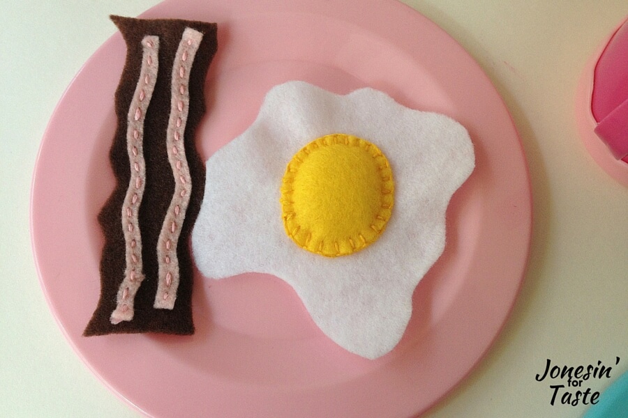 A pink plate with a felt bacon strip and an egg