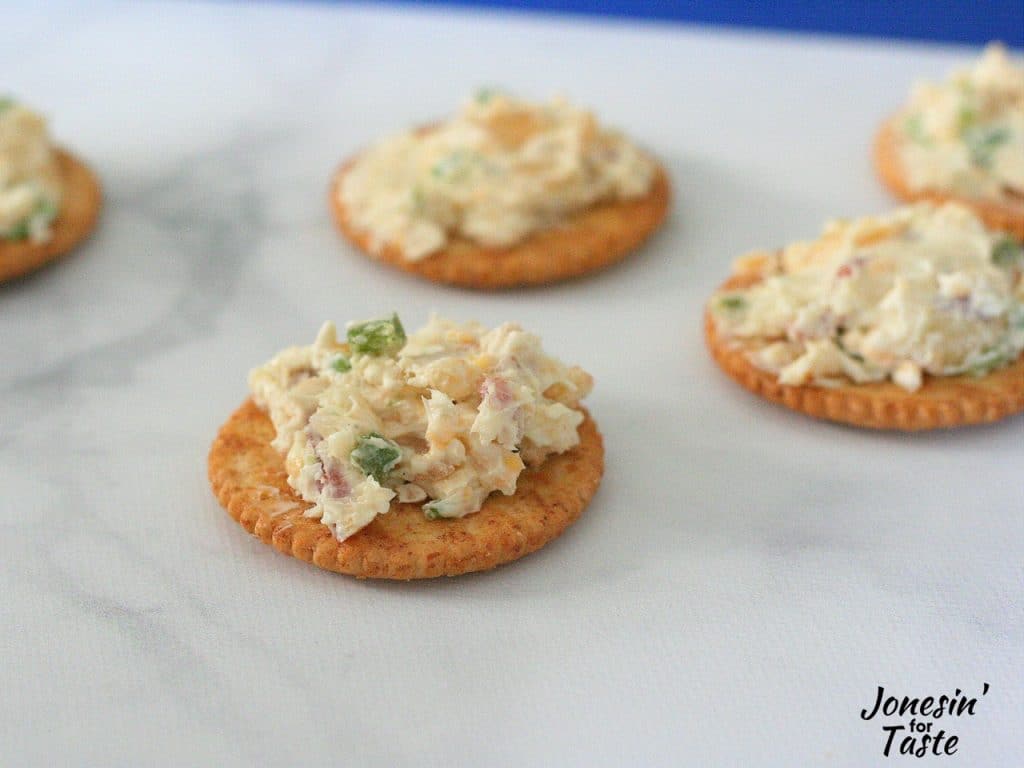 Bacon and Jalapeno cheese log spread on ritz crackers on a marble surface.
