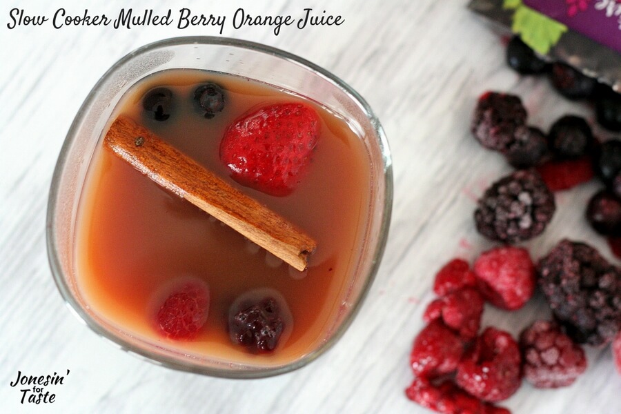 Slow Cooker Mulled Berry Orange Juice viewed from above with a cinnamon stick and extra berries in the glass.
