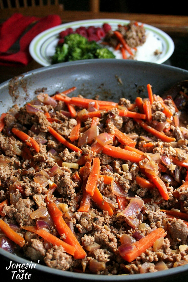 Cooked hamburger, carrots, and onions in a pan.