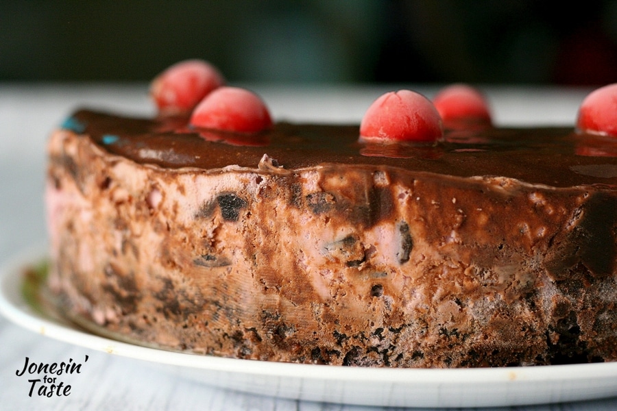 A Cherry Chocolate Ice Cream Cake with Brownie Base topped with chocolate sauce and cherries