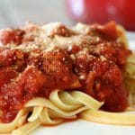 A plate with fettuccine noodles topped with Turkey Spaghetti Sauce and parmesan cheese