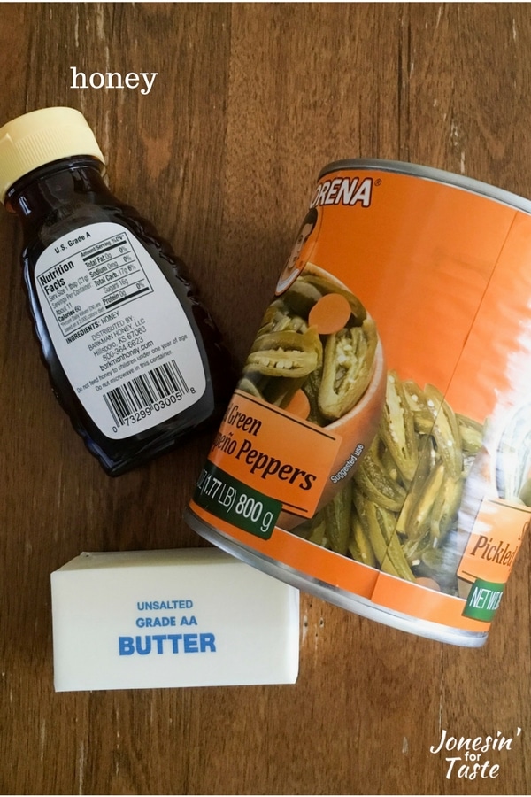 A container of honey, a stick of butter, and a can of sliced jalapeno peppers