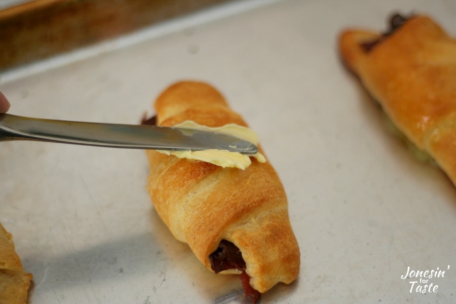 Spreading butter onto a cooked bacon croissant