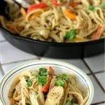 A bowl of chicken fajita pasta with cilantro lime sauce in front of a large cast iron pan full of chicken fajita pasta.