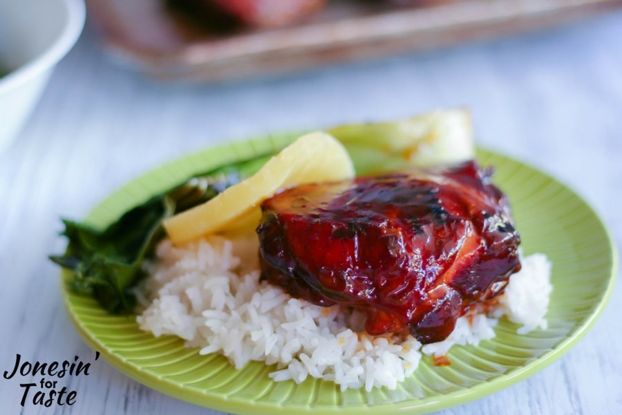 A green plate filled with rice, slow cooker sticky pineapple chicken served with sliced pineapple and baby bok choy