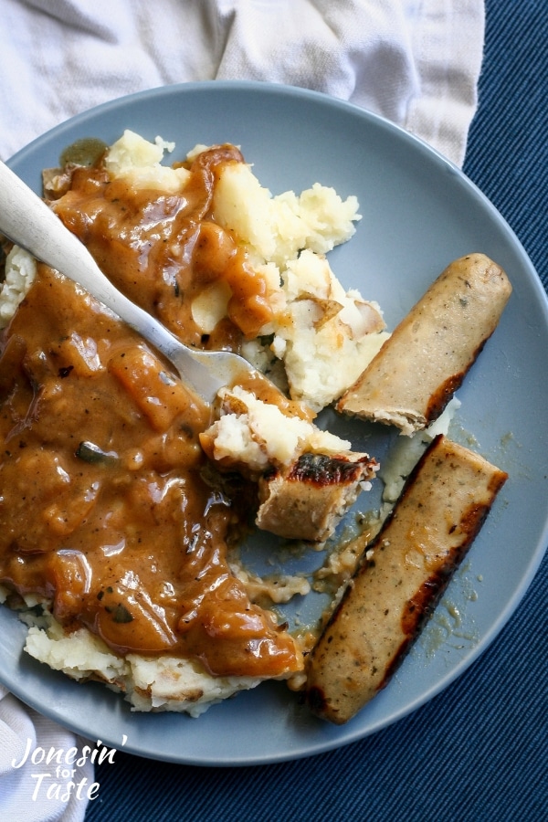 A bite of bangers and mash on a fork on a plate