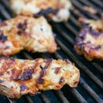 Pieces of buffalo chicken being cooked on a grill.