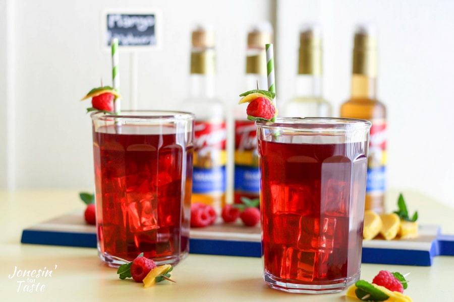 Mango Raspberry Herbal Iced Tea in glass cups with garnishes and straws
