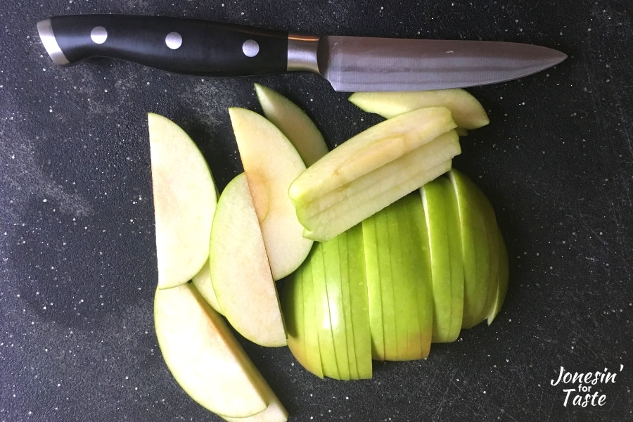 A knife next to sliced granny smith apples