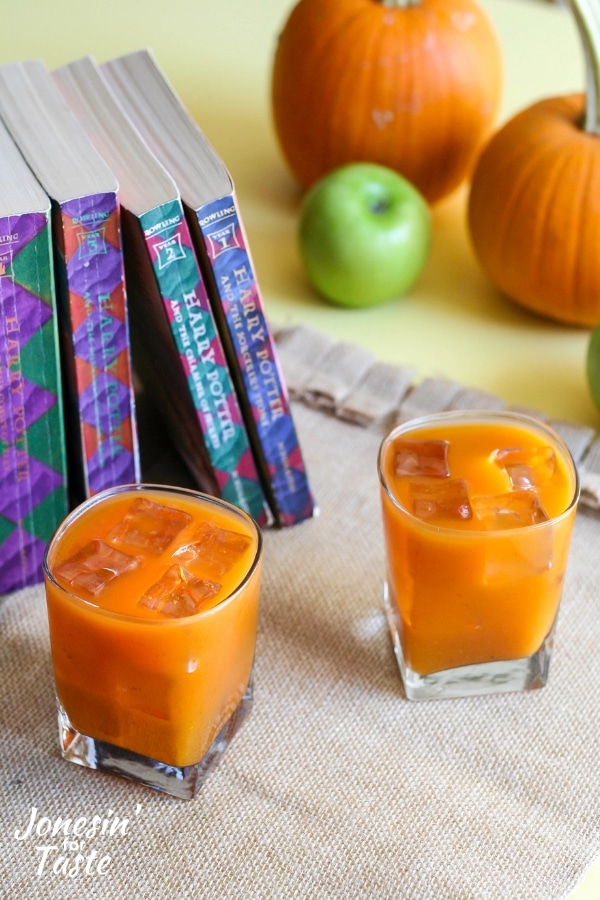 Two glasses of pumpkin juice next to a line of Harry Potter books.