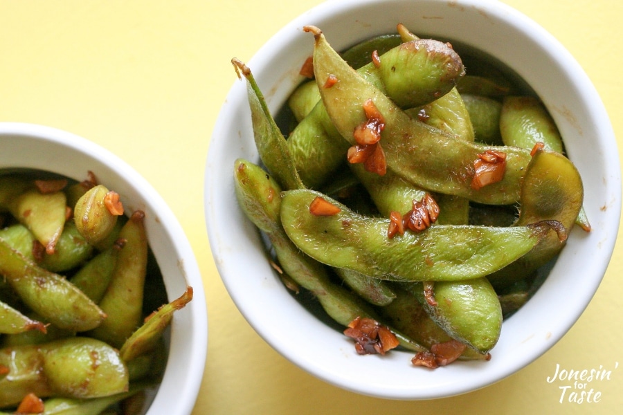 Two white bowls with garlic soy edamame