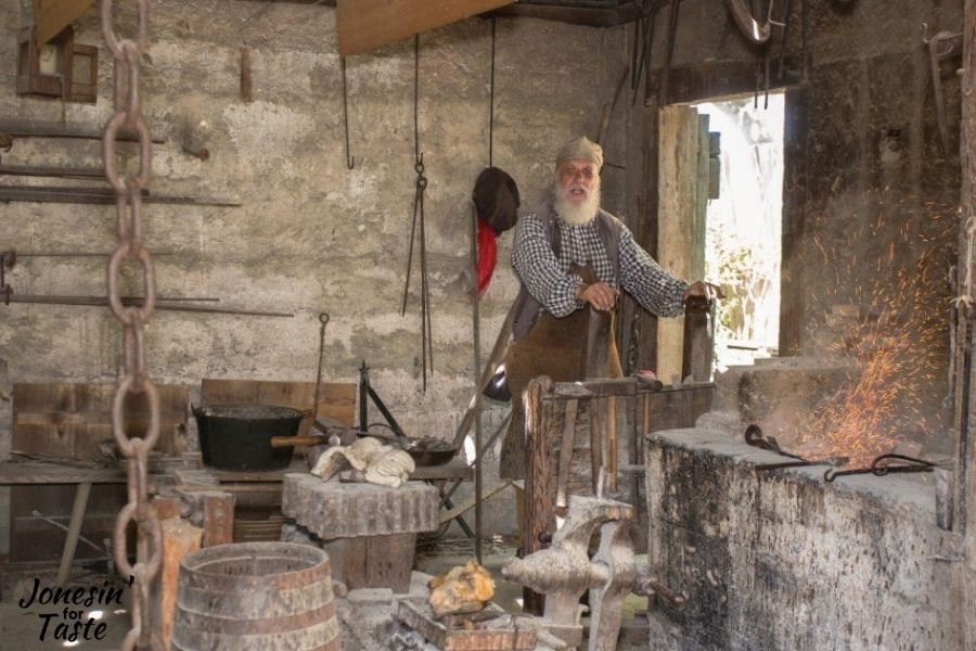 a blacksmith working in his shop at colonial quarters