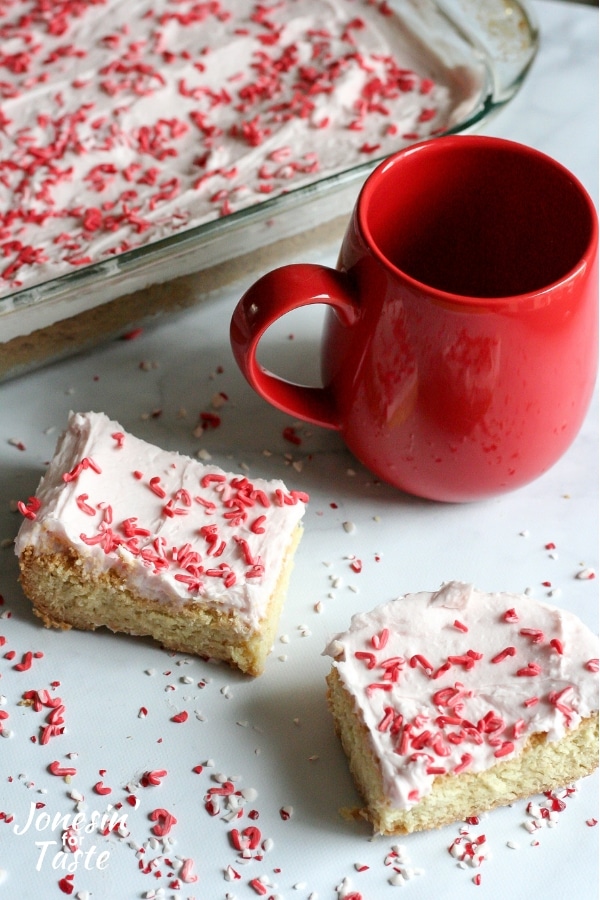 2 iced peppermint cookie bars next to a red mug