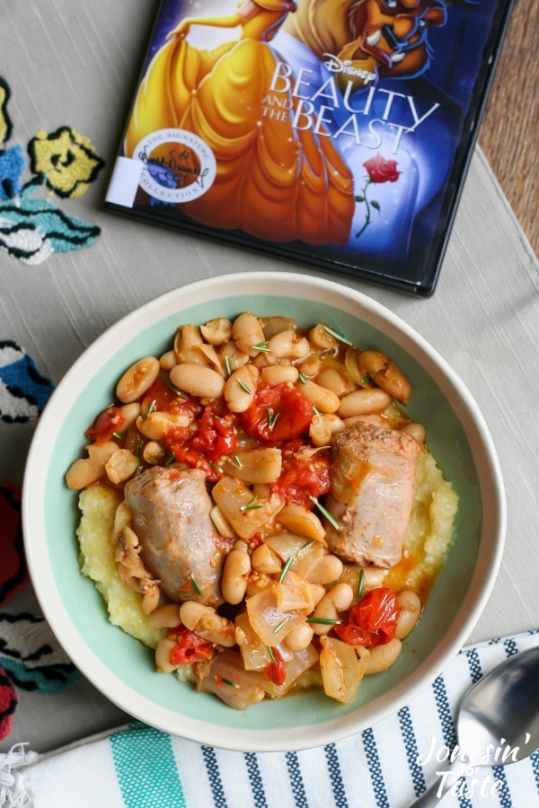 A bowl of polenta, sausage, tomatoes, and beans next to the movie Beauty and the Beast