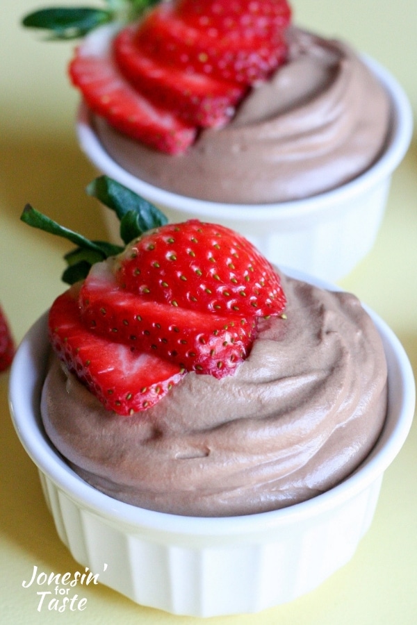Two ramekins with chocolate mousse and sliced strawberries
