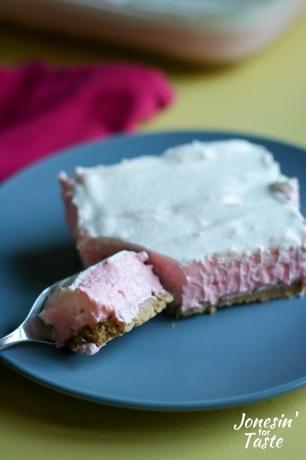 A bite of guava cheesecake on a fork sitting on a blue plate