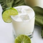 A glass of lemonade with ice and a slice of lime