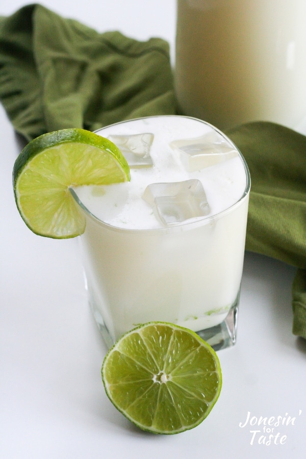 A glass of lemonade with ice and a slice of lime 