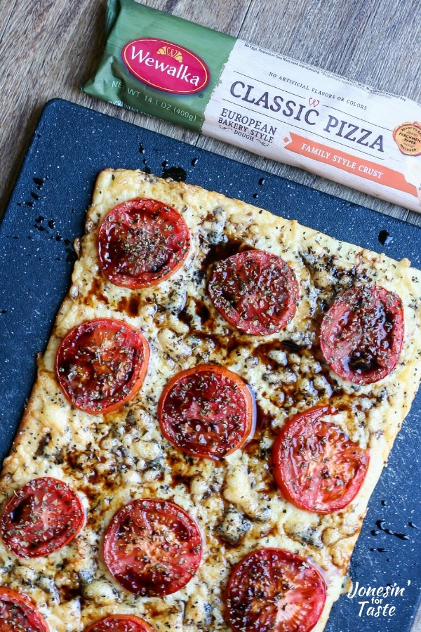 Cooked tomato pizza on a black cutting board