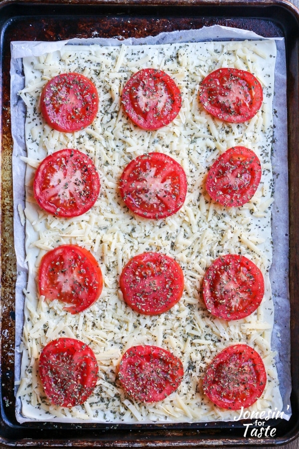 An uncooked tomato pizza on a cookie sheet