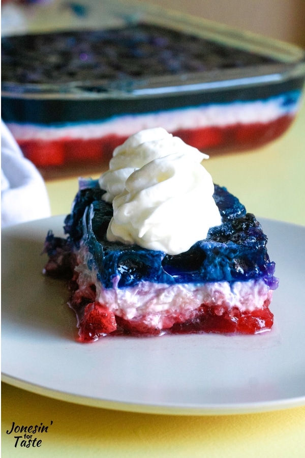 A square of red white and blue jello topped with whipped cream