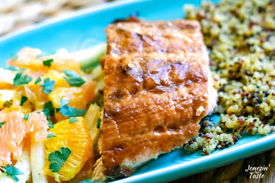 orange bbq salmon on a blue plate with citrus salad and quinoa