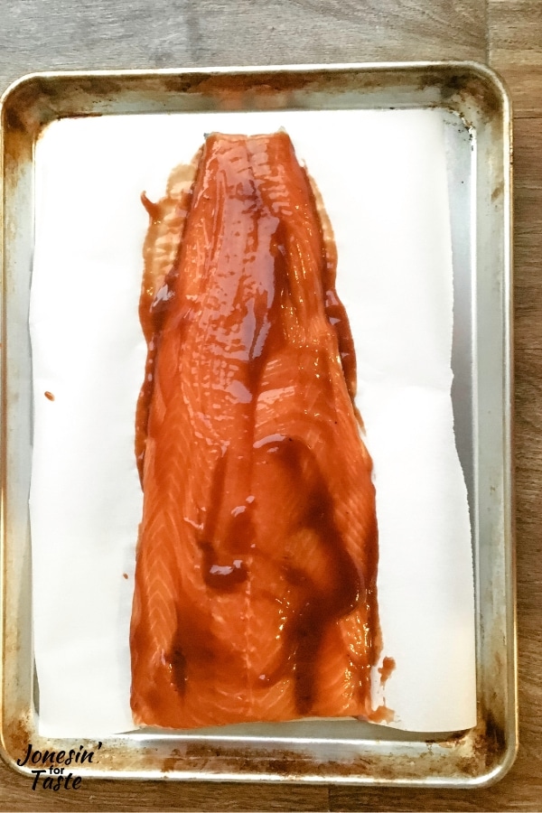 raw salmon covered in bbq sauce on a parchment covered tray