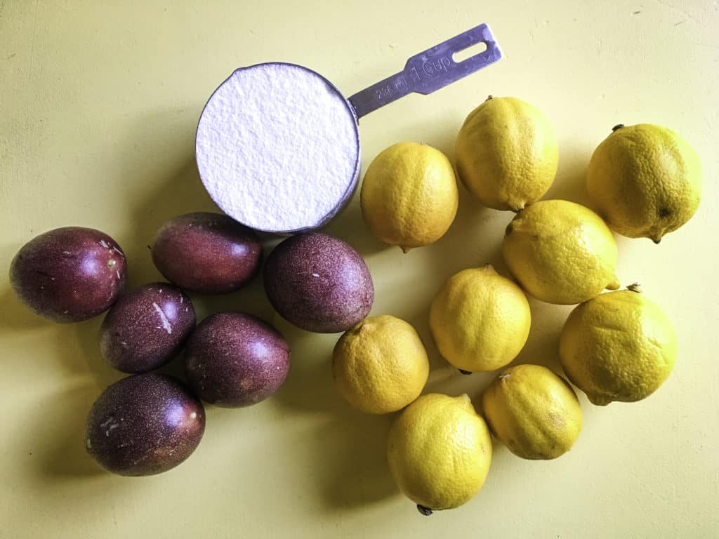 passion fruits, lemons, and a cup of sugar on a yellow table