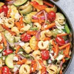 a large pan filled with tortellini and a rainbow of vegetables