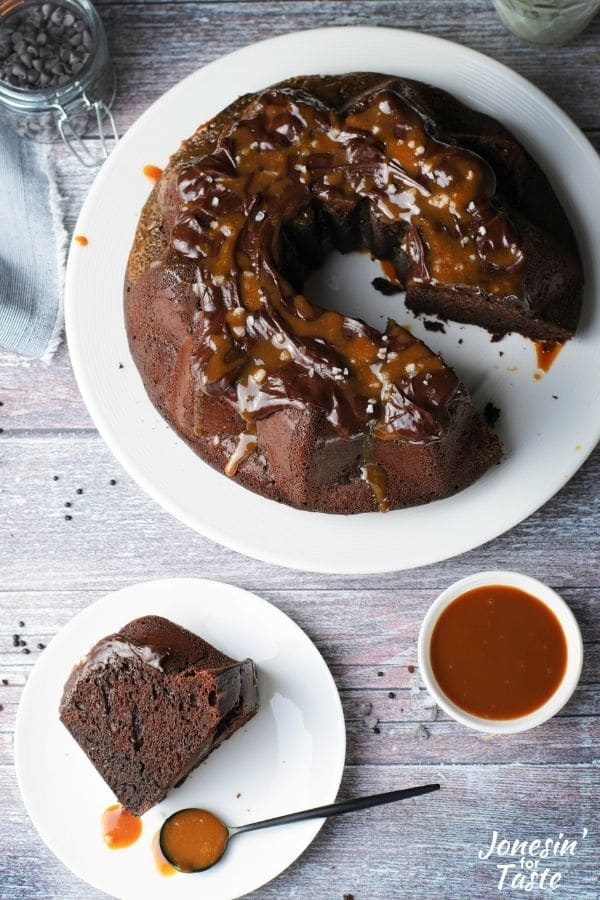 a slice of the bundt cake and a spoon with caramel sauce on a white plate next to the cake and a bowl of caramel