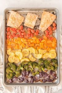 honey mustard salmon fillets with rows of veggies arrange in a rainbow pattern on a sheet pan