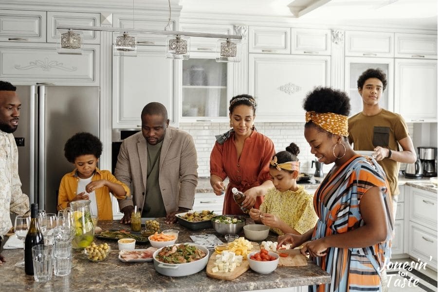 aa family gathering around a kitchen island dishing up various foods for themselves and others