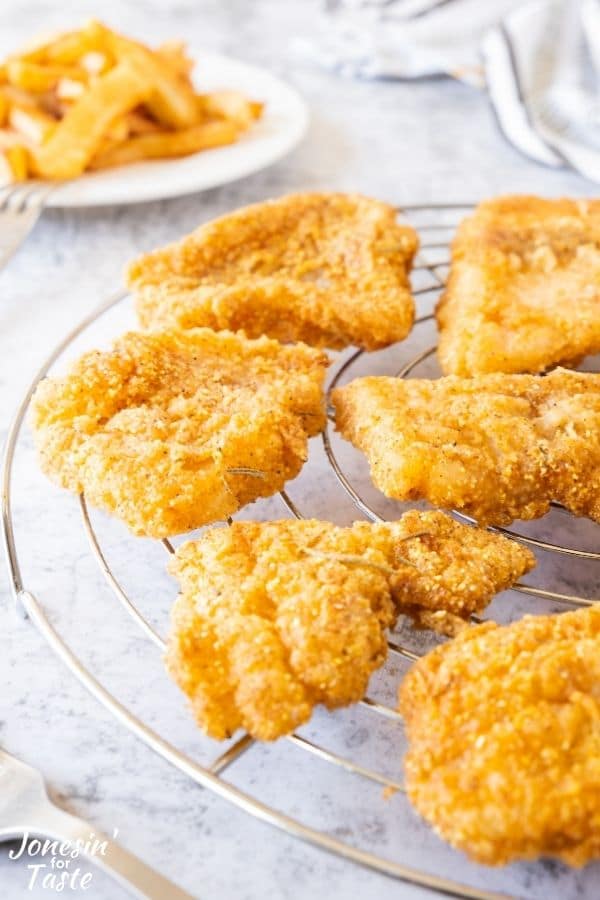fried fish pieces sitting on a metal rack