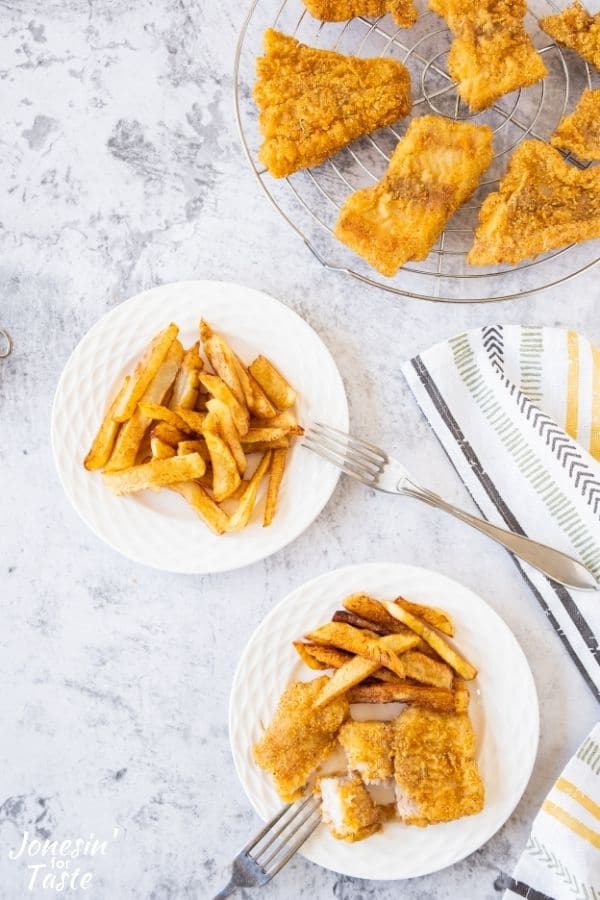 a plate of fish and chips next to a plate of chips and a rack of fried fish