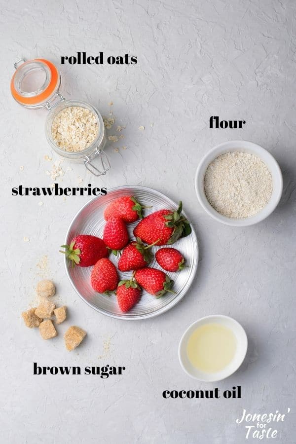 containers holding rolled oats, flour, coconut oil, brown sugar, and fresh strawberries
