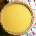 a golden yellow vanilla pie with a light golden brown crust sitting on a red and white tea towel